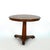 A round fruitwood center table with a plank-built top and molded edge above a plain frieze. The top is raised on a faceted...