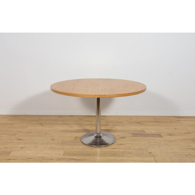 This dining table was manufactured in Denmark during the 1970s. The tabletop is crafted from oak wood. The table has...