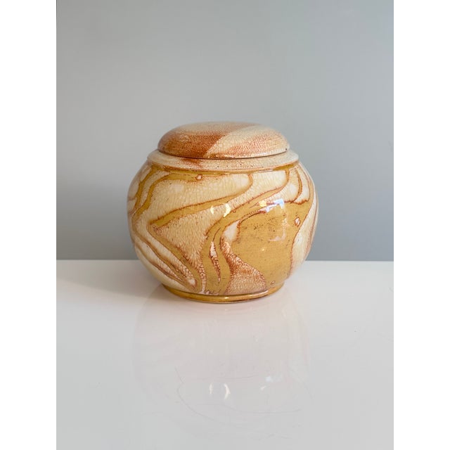 Handcrafted studio ceramic lidded box with a harmoniously rounded body and lid. The surface features an expressive glaze...