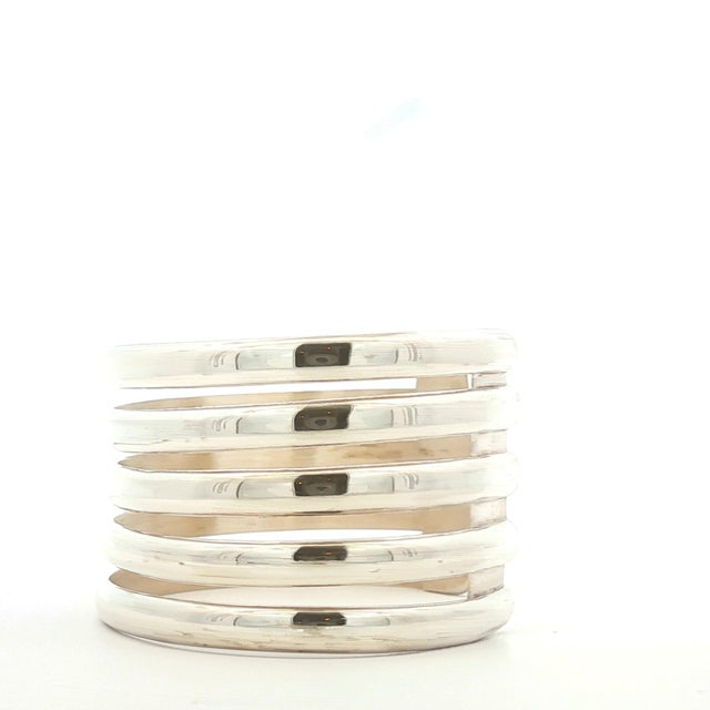 This is a mid-20th century modern cuff bracelet crafted from sterling silver. The design features five parallel bands with...