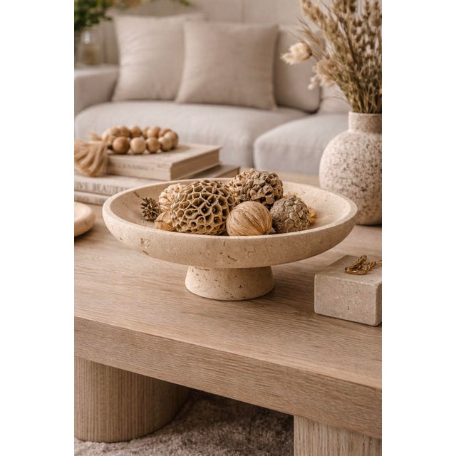 A beautifully sculptural travertine-style pedestal bowl featuring a wide shallow dish raised on a minimalist pedestal...