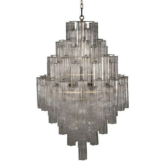 This chandelier showcases a cascading, tiered design of textured glass arranged in staggered symmetry. Its clear glass and...