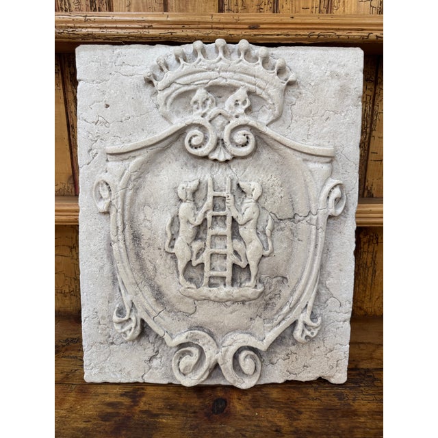 A beautifully aged Italian stone plaque featuring the Cambiaso family coat of arms, carved in elegant relief with a...