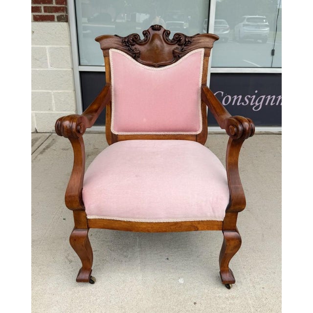This Victorian walnut armchair features a carved crest rail with scrolling floral details, graceful scroll arms, and...