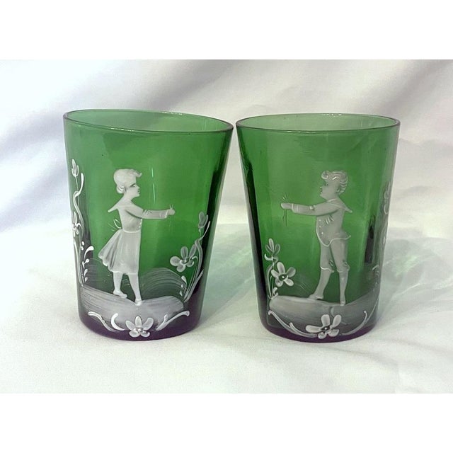 Beautiful pair of Victorian green glass tumblers with Mary Gregory enamel illustrations of a boy and a girl, each reaching...