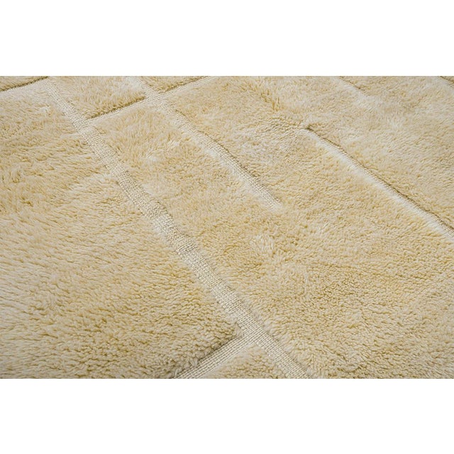 Textured hand-knotted wool rug in a soft Pastel Yellow hue, featuring a subtle, geometric grid design. This minimalist...