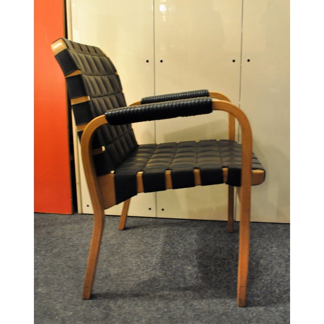 These two model 46 armchairs feature curved birch wood, printed leather, and leather ribbon. They were produced in 1947 by...