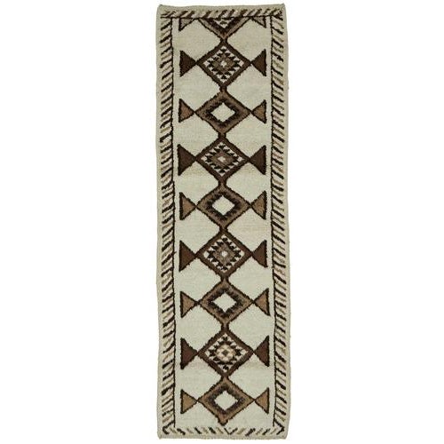 This exquisite runner rug is a rare example of tribal craftsmanship, hand-knotted by the women of the Herki tribe during...