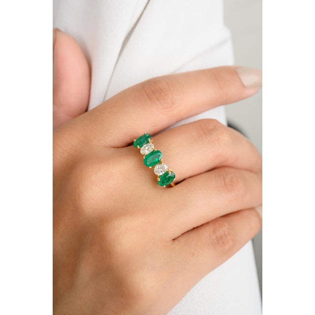 This exquisite wedding band features five stones set in 18K yellow gold: three stunning oval-cut emeralds alternating with...