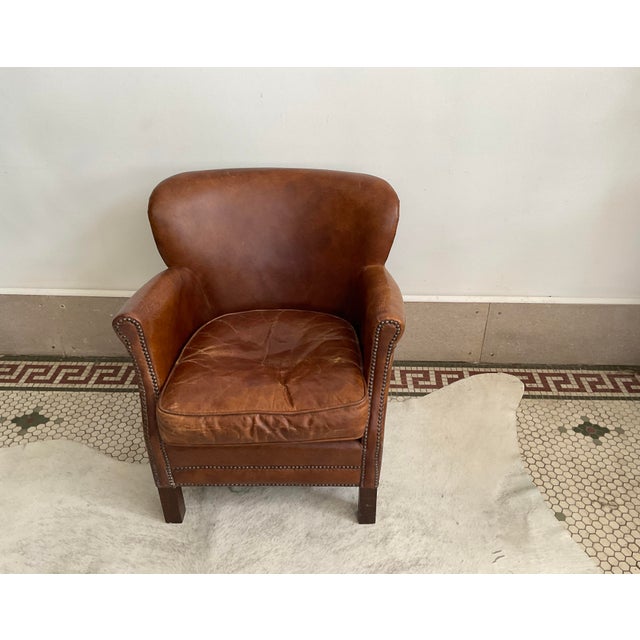 Bring timeless warmth and rich character into your space with this classic vintage distressed brown leather club chair....