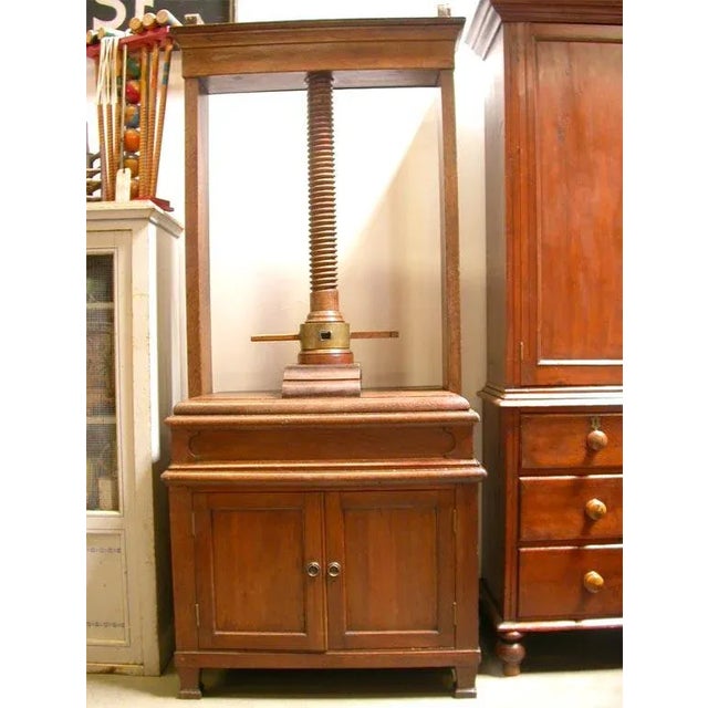A Dutch 18th century oak linen press resting on a later two door cabinet. The press has a central turned screw device for...