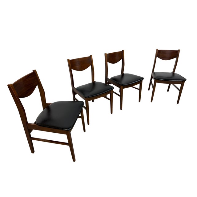 A handsome set of four Mid-Century Modern walnut dining chairs, circa 1960s, featuring clean architectural lines and a...