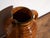 This antique folk glazed pottery jug is a spouted jug with a mottled amber glaze and a side handle . It originates from...