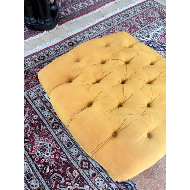 Elegant vintage Louis XVI–style ottoman featuring deep button tufting in a rich golden mustard upholstery, set over a...