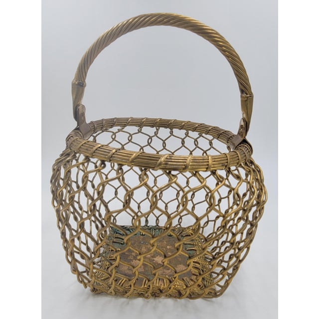 A charming vintage decorative basket crafted from heavy-gauge brass wire. This piece features an intricate, open-weave...