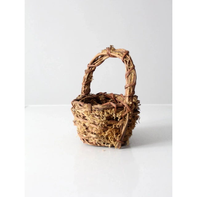 Vintage twig basket featuring a rustic woven form with natural moss entwined throughout, creating a charming nest-like...