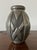 Hammered pewter vase, oval in shape, with raised geometric decorations and a distinctive hammered finish. The shapes...