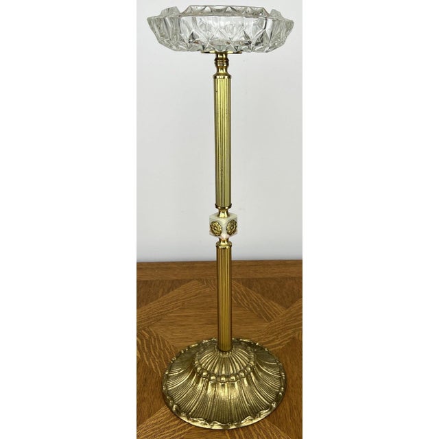 An elegant Vintage ashtray stand featuring a beautifully cut crystal bowl raised on a decorative brass and onyx column....