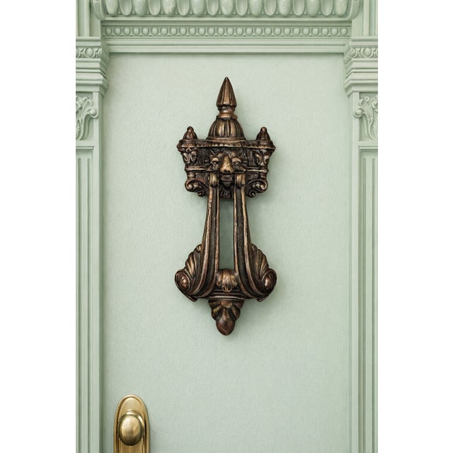 This impressive antique bronze door knocker features an ornate architectural design with strong vertical lines, scrolling...