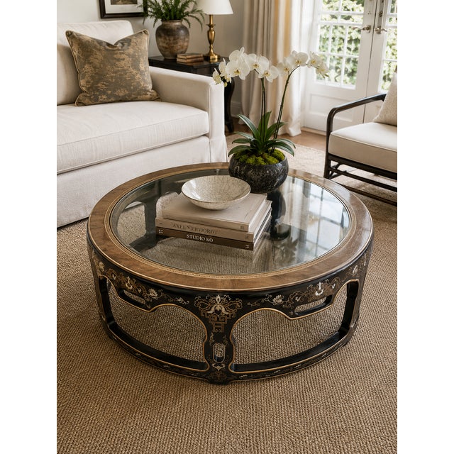 A striking mid-century Drexel coffee table featuring hand-painted Chinoiserie motifs, a circular glass insert, and an...