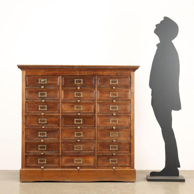 Oak filing cabinet, twenty-one extractable drawers with flap front. Chiselled and gilded metal inkwells and label holders....