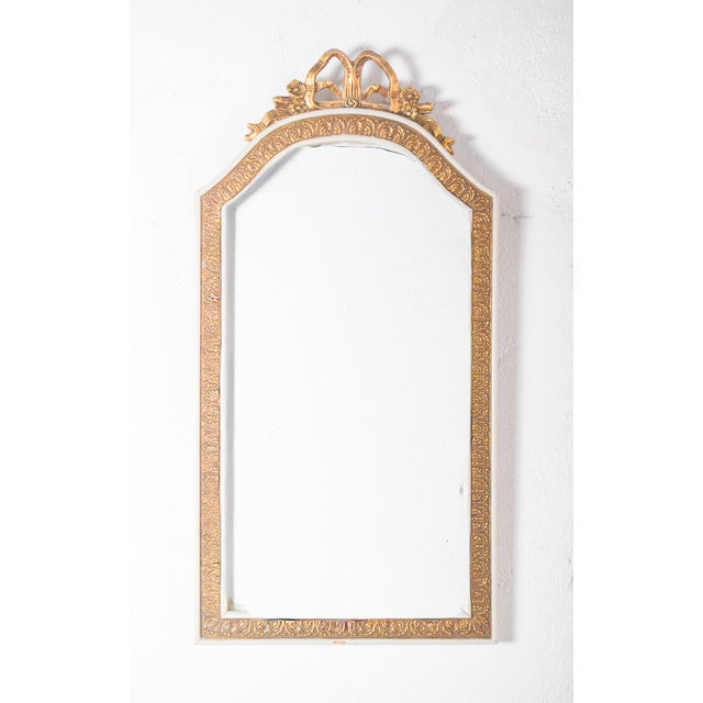 This refined rectangular mirror is framed in wood, painted in white and adorned with elegant gilt accents. The frame is...