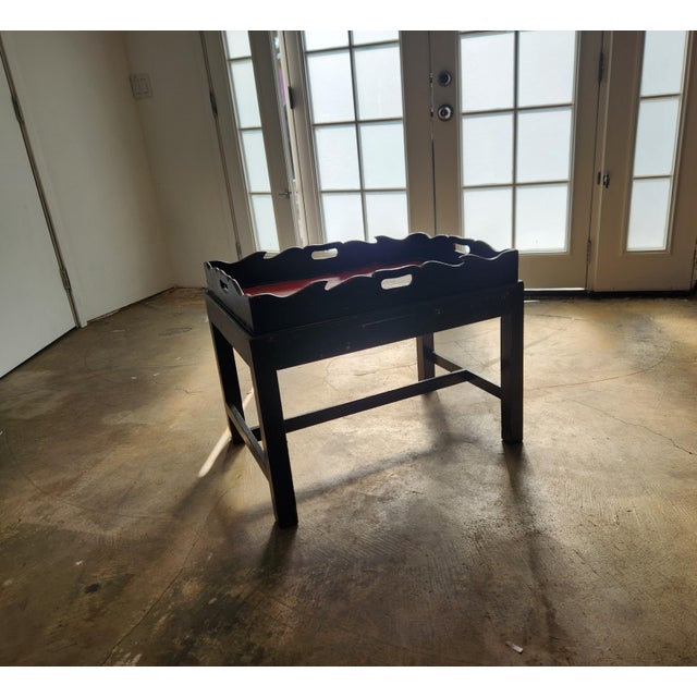 Carved wood Chinoiserie Butler's Tray table. Black and red high-gloss lacquer cradle the carved island landscape of trees,...