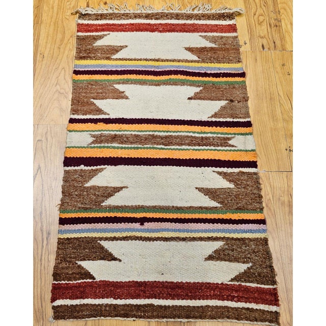 This vintage Navajo area rug, handwoven in the late 20th century, is a striking example of Native American textile...