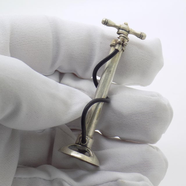 This vintage silver decorative object depicts a detailed bicycle pump miniature, crafted as a mechanical novelty or...