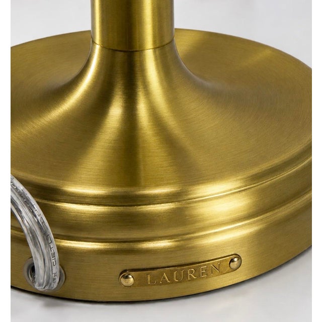 A timeless pair of Ralph Lauren Home gold brass table lamps featuring elegantly turned silhouettes and substantial stepped...