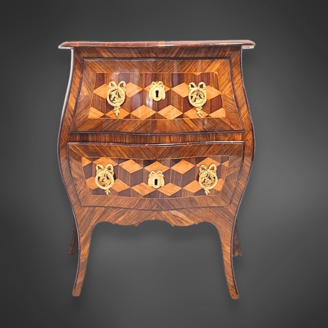 A small, two-drawer chest, also known in this version as a sauté chest. The body is curved and bombé on all sides, flowing...