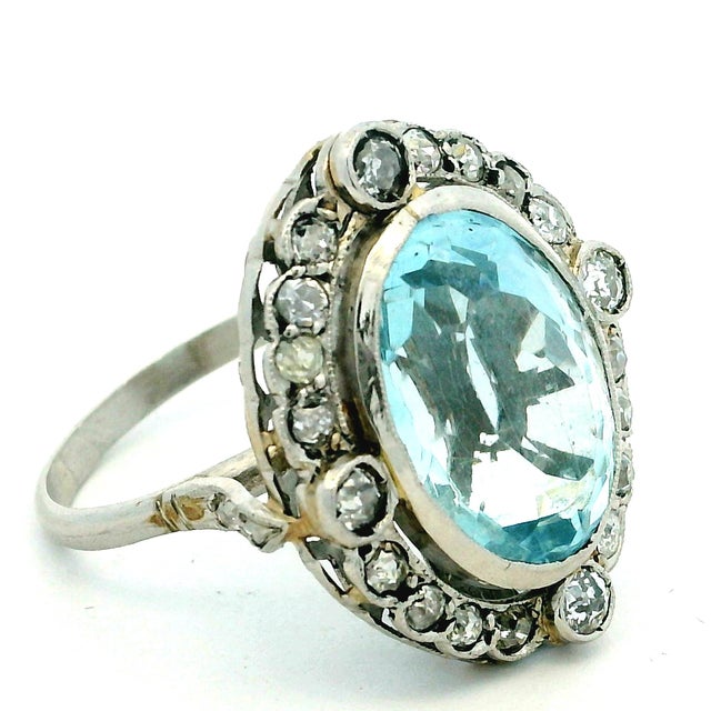 A beautifully proportioned Art Deco ring centered with an approximately 10 carat oval aquamarine, displaying a soft,...