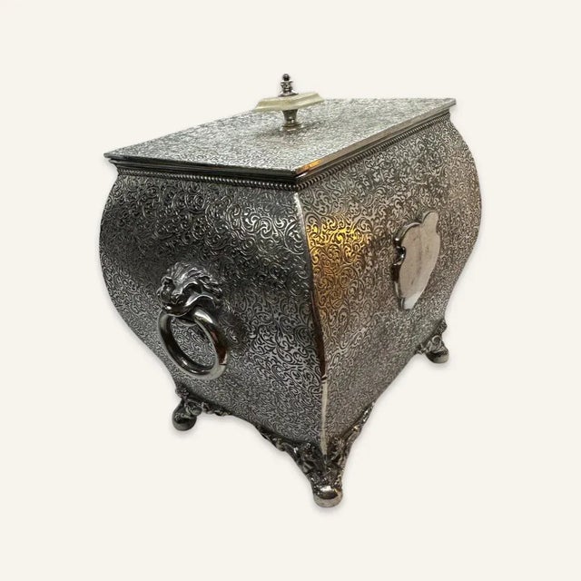 Handsome silver-filled bombe box with scrollwork decoration on the sides and lion legs terminating in bun feet. The makers...