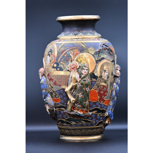 A rich tapestry of color, texture, and spiritual symbolism, this early 20th-century Japanese Satsuma-style vase is an...
