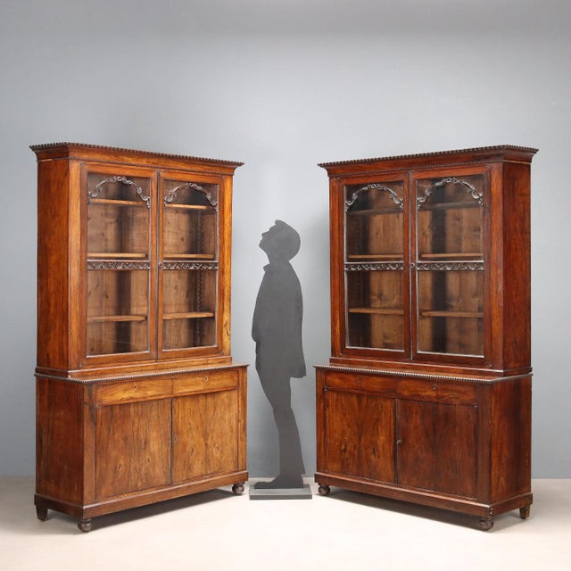 Pair of rosewood veneered bookcases. The upper part features glass doors, embellished with leaf carvings and scrolls....