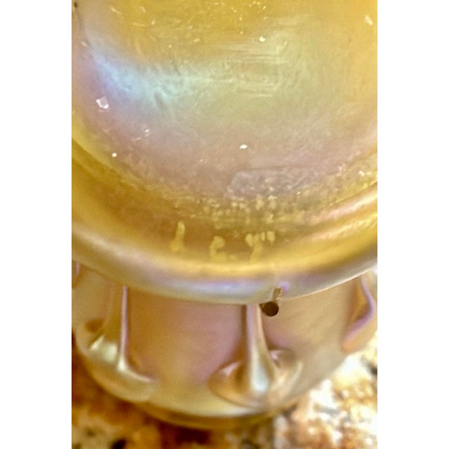 It is crafted from Favrile glass, a signature iridescent art glass patented by Louis Comfort Tiffany in 1894. The vase...