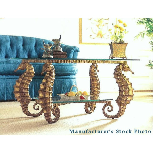 A Coastal Seahorse Coffee Table. Features a sturdy metal frame with legs formed into Seahorses and a rich gilt finish....