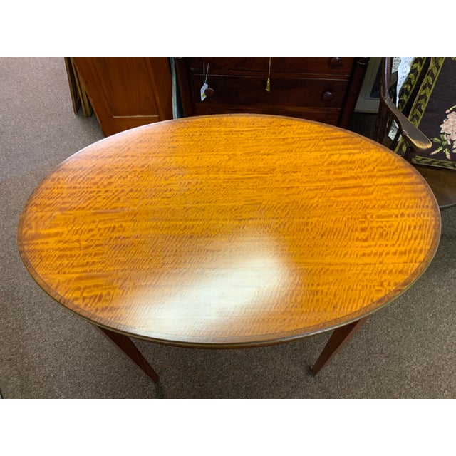 Early 20th century English Edwardian table. Beautiful satinwood top with banded inlay, mahogany base.Leg on metal castors.