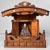 Small wooden temple with a curved roof, finely cut details, and metal ornaments in brass and silver tones. Dimensions:...