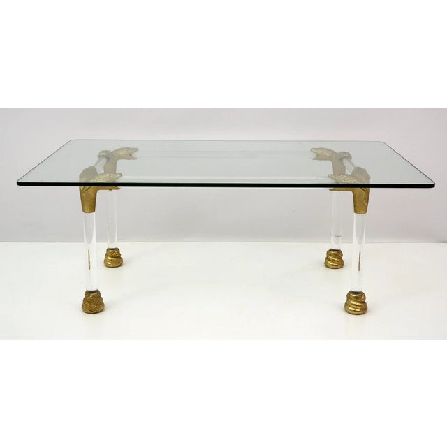 Mid-Century acrylic glass and brass coffee table with snake head detail. This elegant item was designed in the 1970's in...