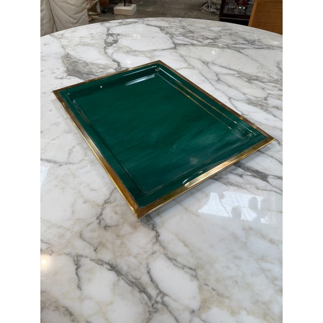 Elegant vintage serving tray featuring a rich emerald green lacquered surface framed by a polished brass border. The clean...
