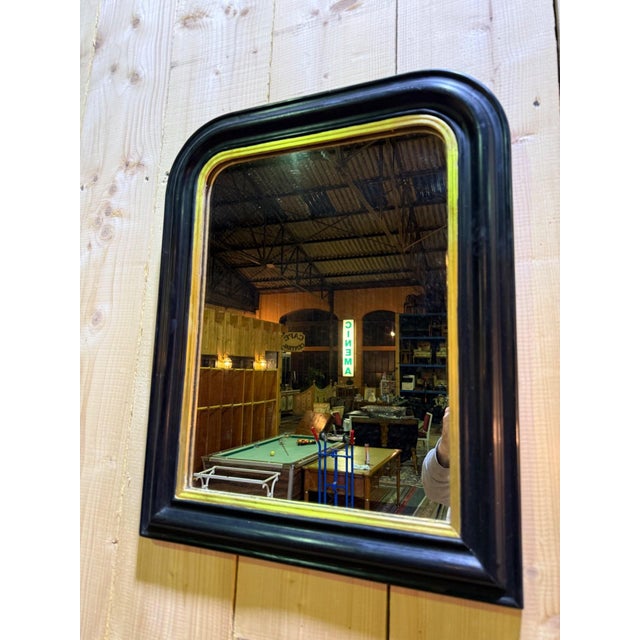 A napoleon iii period mirror, circa 1850-1880, in blackened lacquered wood with a curved, molded profile. the frame...