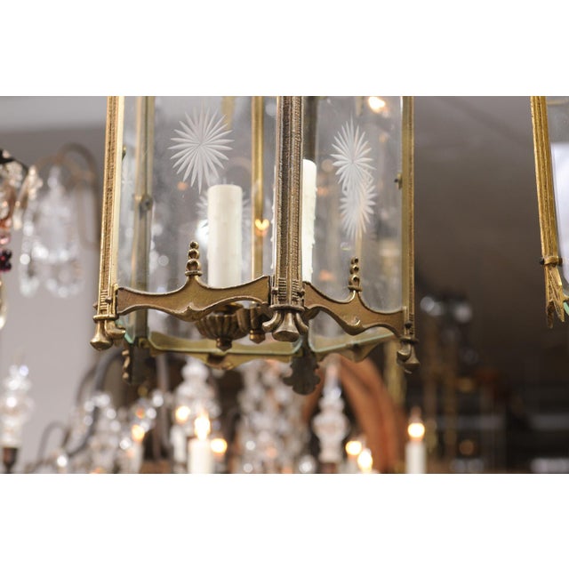 A French hall lantern executed in gilt bronze with etched sunburst glass panels and ornate scrolling crest details. The...