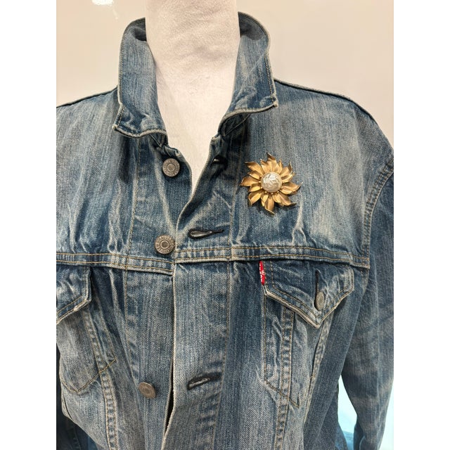 Vintage Gold Tone Sunburst Flower Brooch With Faux Pearl Description This brooch features a sculptural sunburst flower...