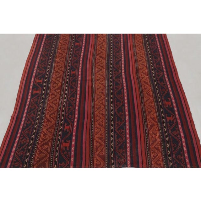 Handwoven in wool and originating circa 1950-1960, this 4x5 vintage Persian kilim is a masterfully curated tribal addition...