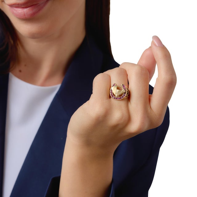 This bold Retro horseshoe signet ring showcases a vibrant arrangement of 18 round brilliant cut rubies totaling...