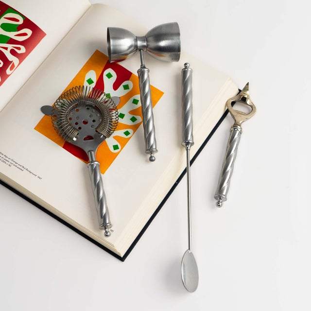 An elegant set of four vintage bar tools featuring a classic twist metal handle design- includes a stirring spoon, jigger,...