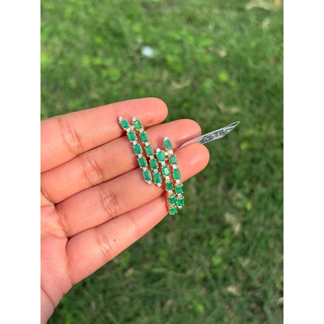 These emerald-cut emerald and diamond double linear dangle earrings crafted in 14K yellow gold. They feature natural...