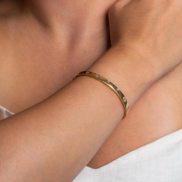 This is part of Chairish’s Fine Jewelry assortment. This is a beautiful, weighty gold bangle with double baguette...