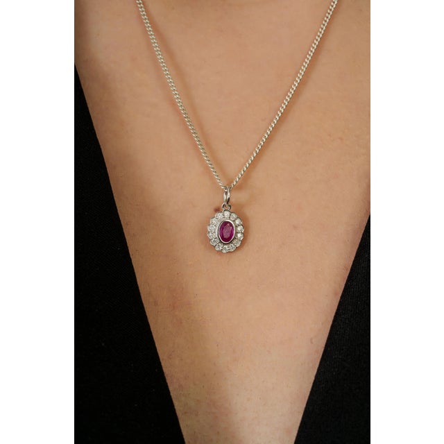 This halo pendant featuring a 0.28 carats oval ruby set in 14K white gold. The oval measuring approximately 4.92 x 3.37...